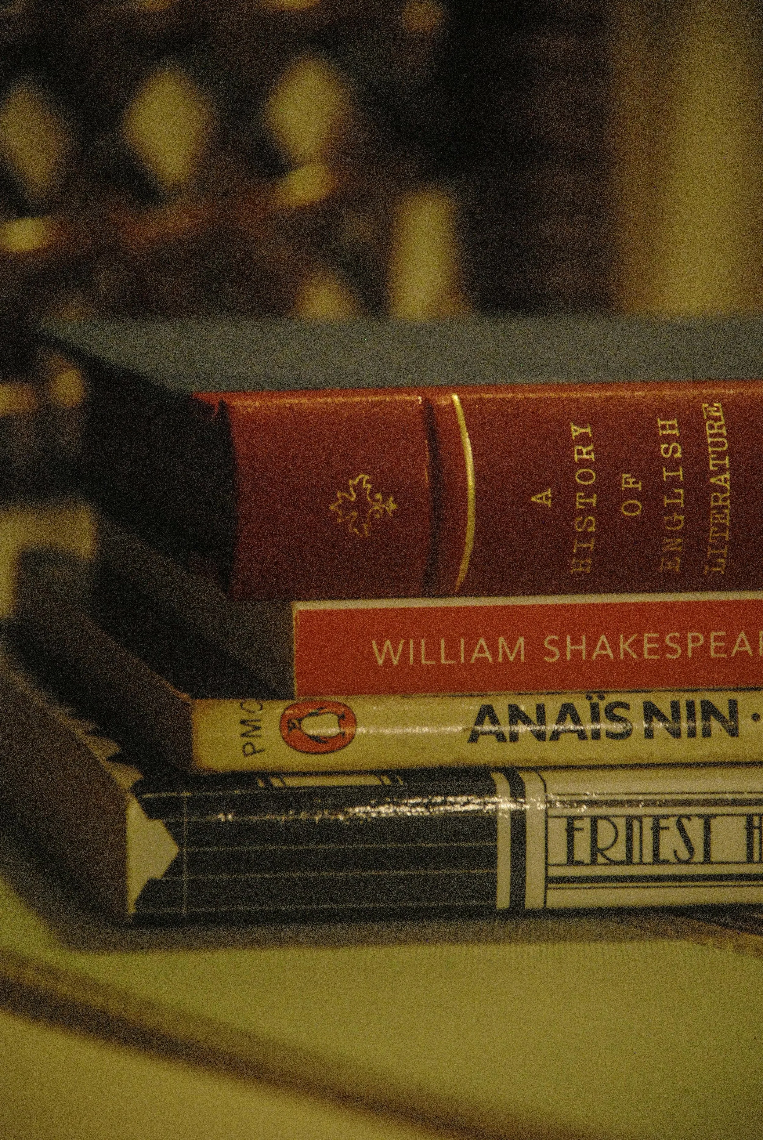 A stack of five books on a surface, including 'A History of English Literature' and books by William Shakespeare and Anaïs Nin.