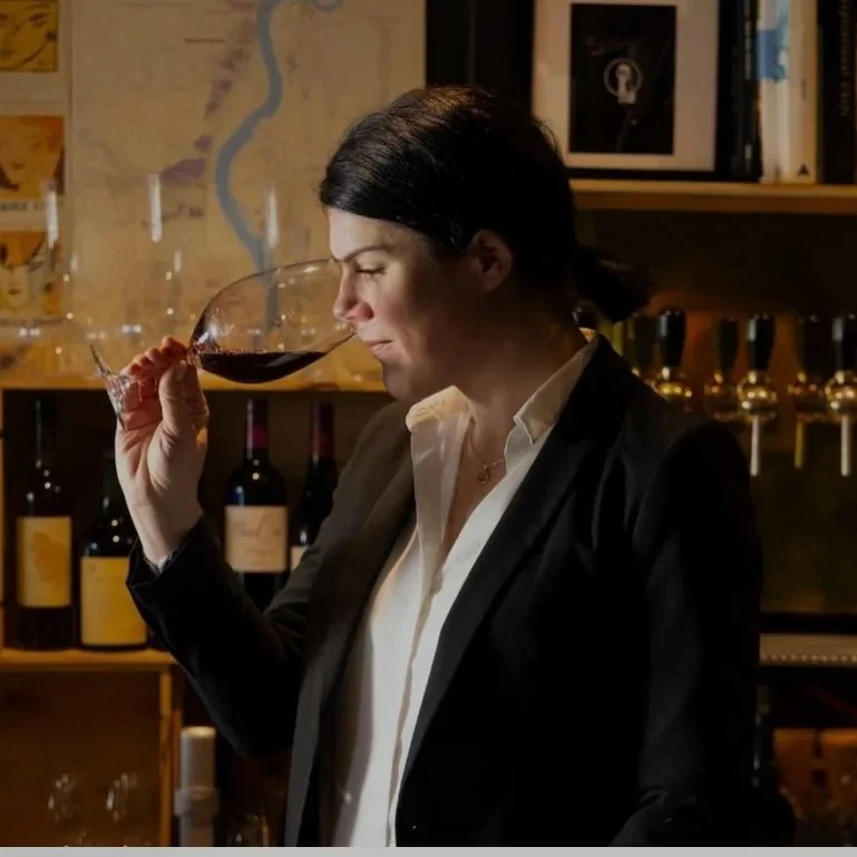 Woman with short brown hair smelling red wine in a wine glass