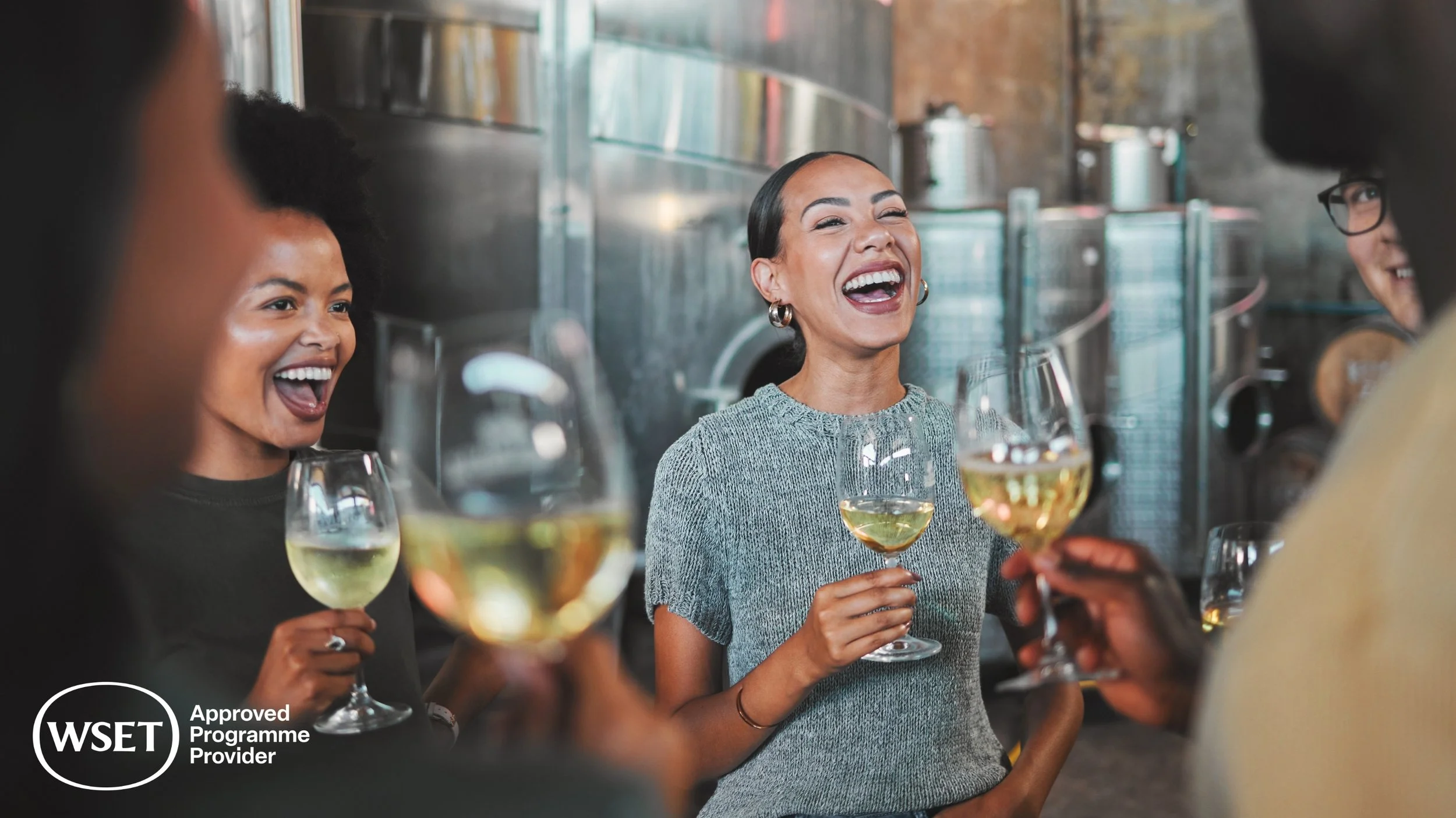 Group of friends enjoying drinks and laughter together in a bar or restaurant setting.