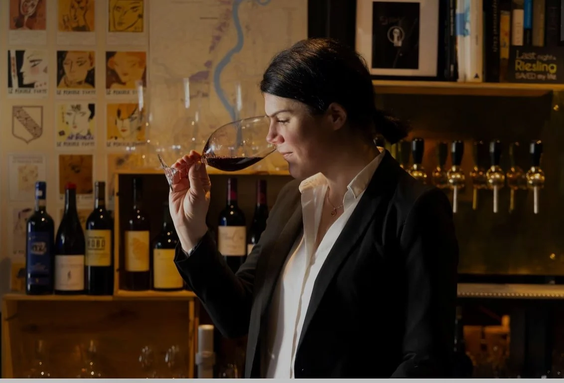 Woman with short brown hair smelling red wine in a wine glass