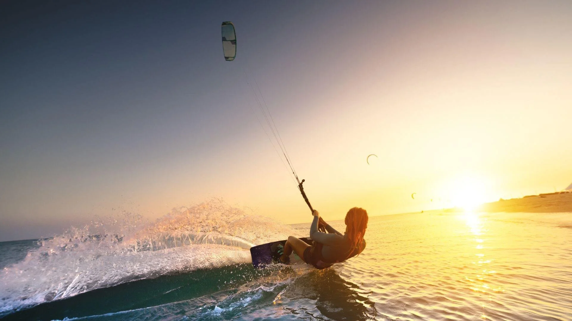 Farbenfroher Sonnenuntergang mit Frau beim Kitesurfen