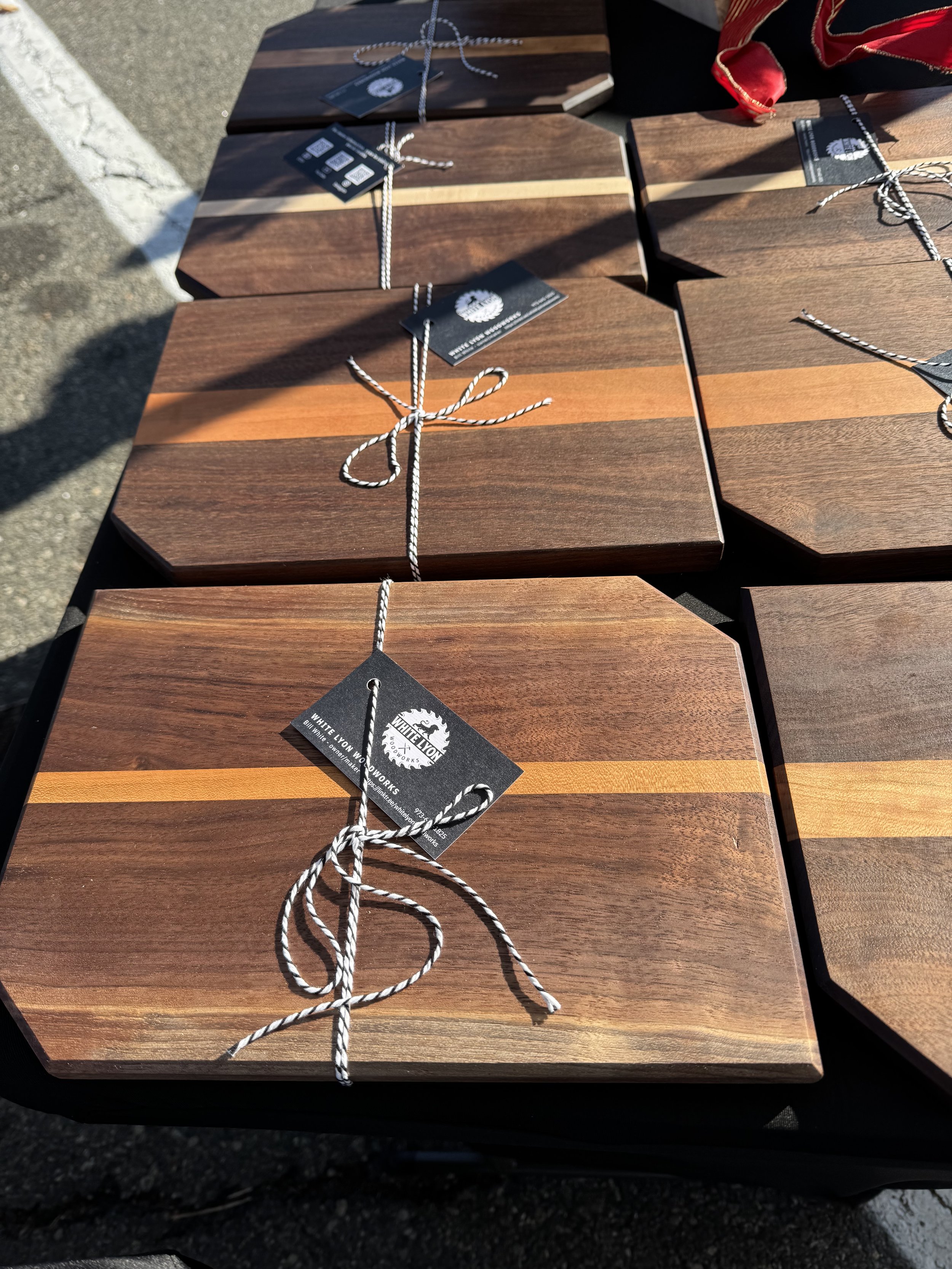Multiple wooden chopping boards tied with black and white string, displayed on a table at an outdoor market.