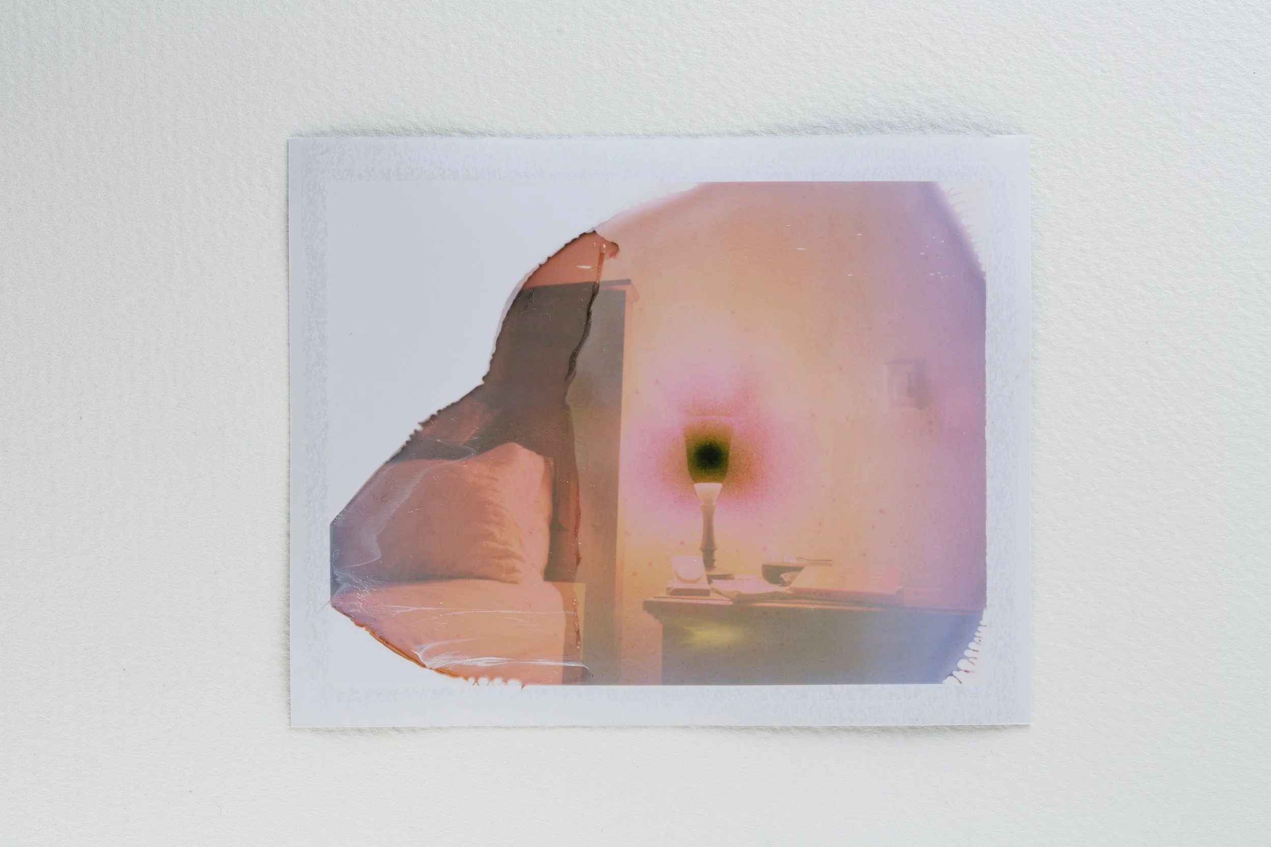 a polaroid photograph using expired film of a bed and lamp to accompany a poem abut the winter solstice.