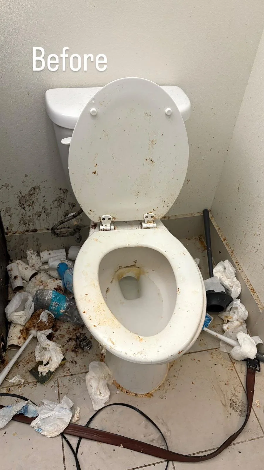 A dirty toilet with a stained bowl and a stained seat, surrounded by trash, toilet paper, a water bottle, cleaning supplies, and other debris on the floor and sides.