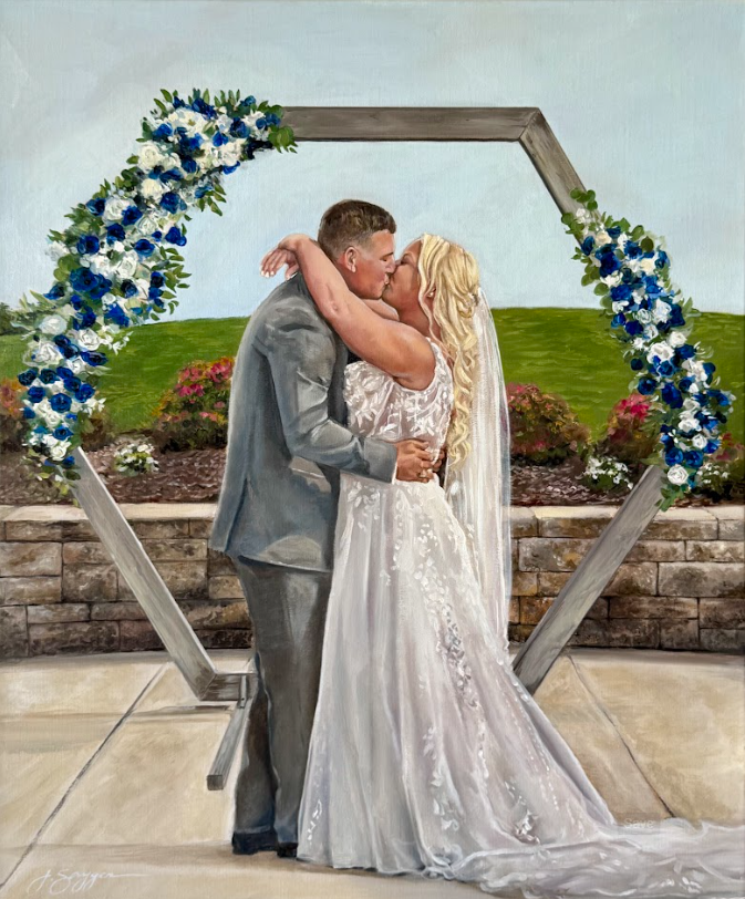 A bride and groom sharing a kiss under a heart-shaped floral arch during their wedding ceremony outside.