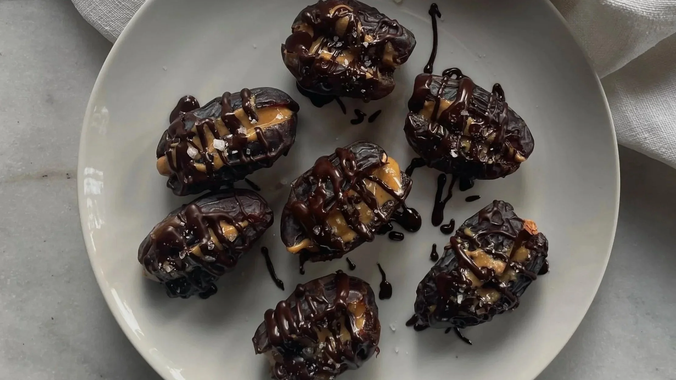 Prugne ripiene di burro d'arachidi, coperte di cioccolato fondente e decorato con scaglie di sale