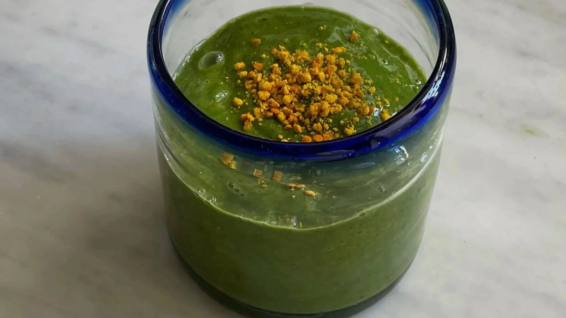 Vaso di vetro con una bevanda verde decorata con granella di nocciole.