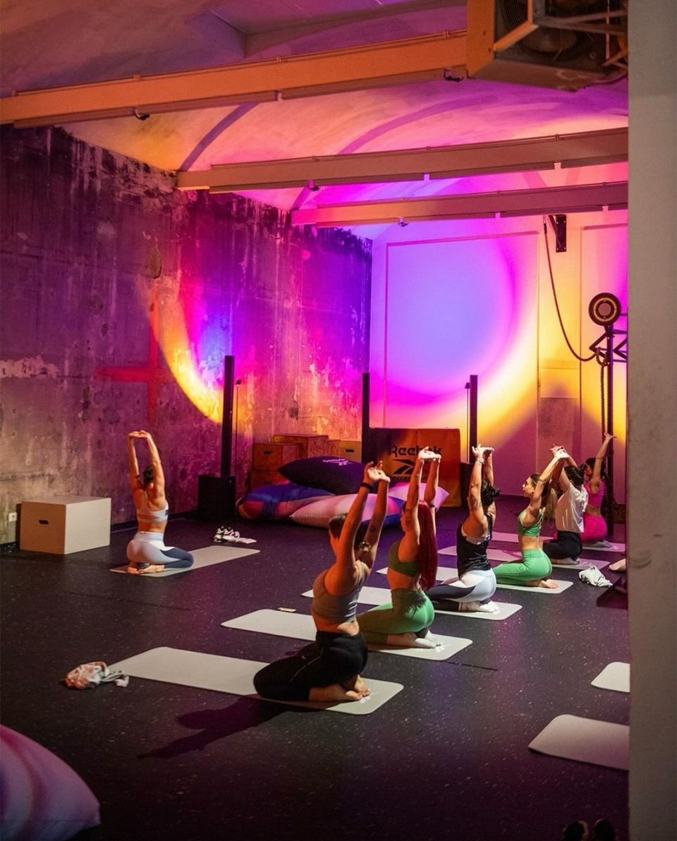 Gruppo di persone che praticano yoga in un ambiente con luci colorate