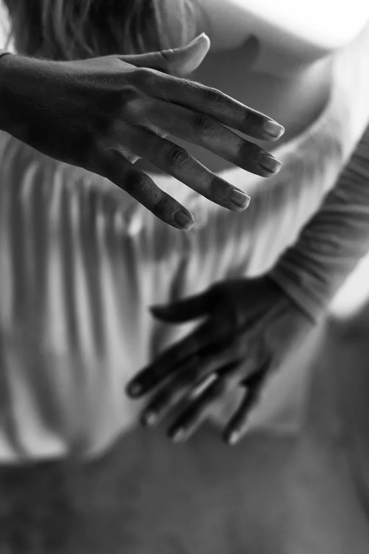 Due mani che si sfiorano, una sopra l'altra, in una foto in bianco e nero.