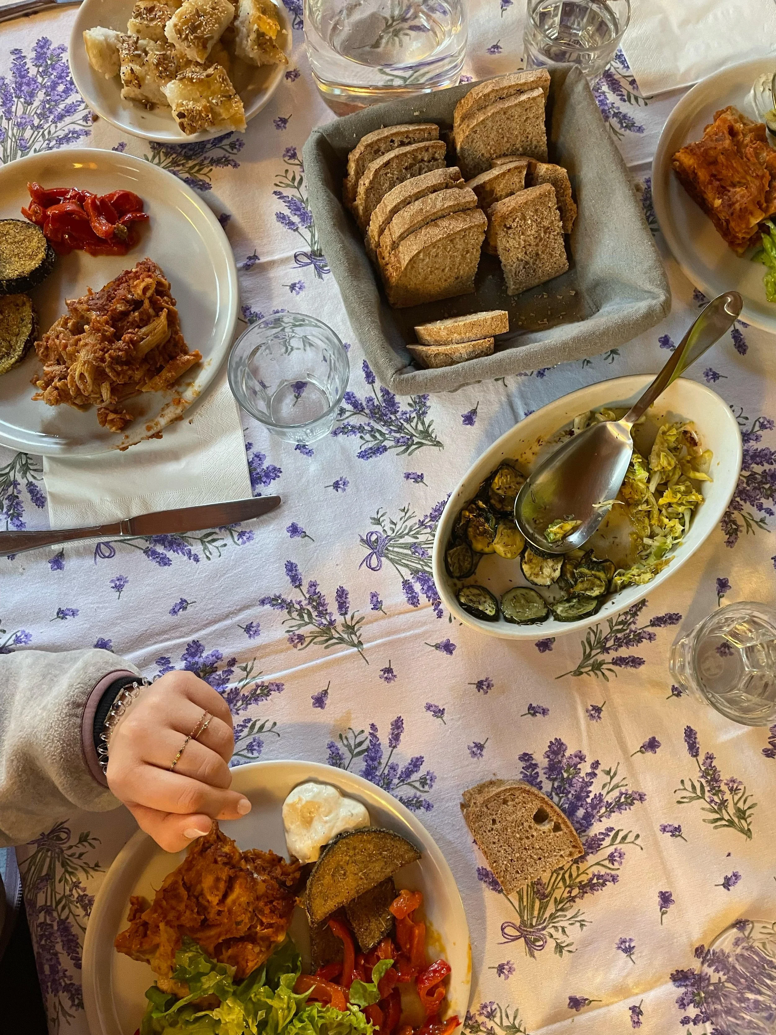 Un tavolo con vari alimenti tra cui pane integrale, insalata di verdure, carne fritta con pane, e altre pietanze.