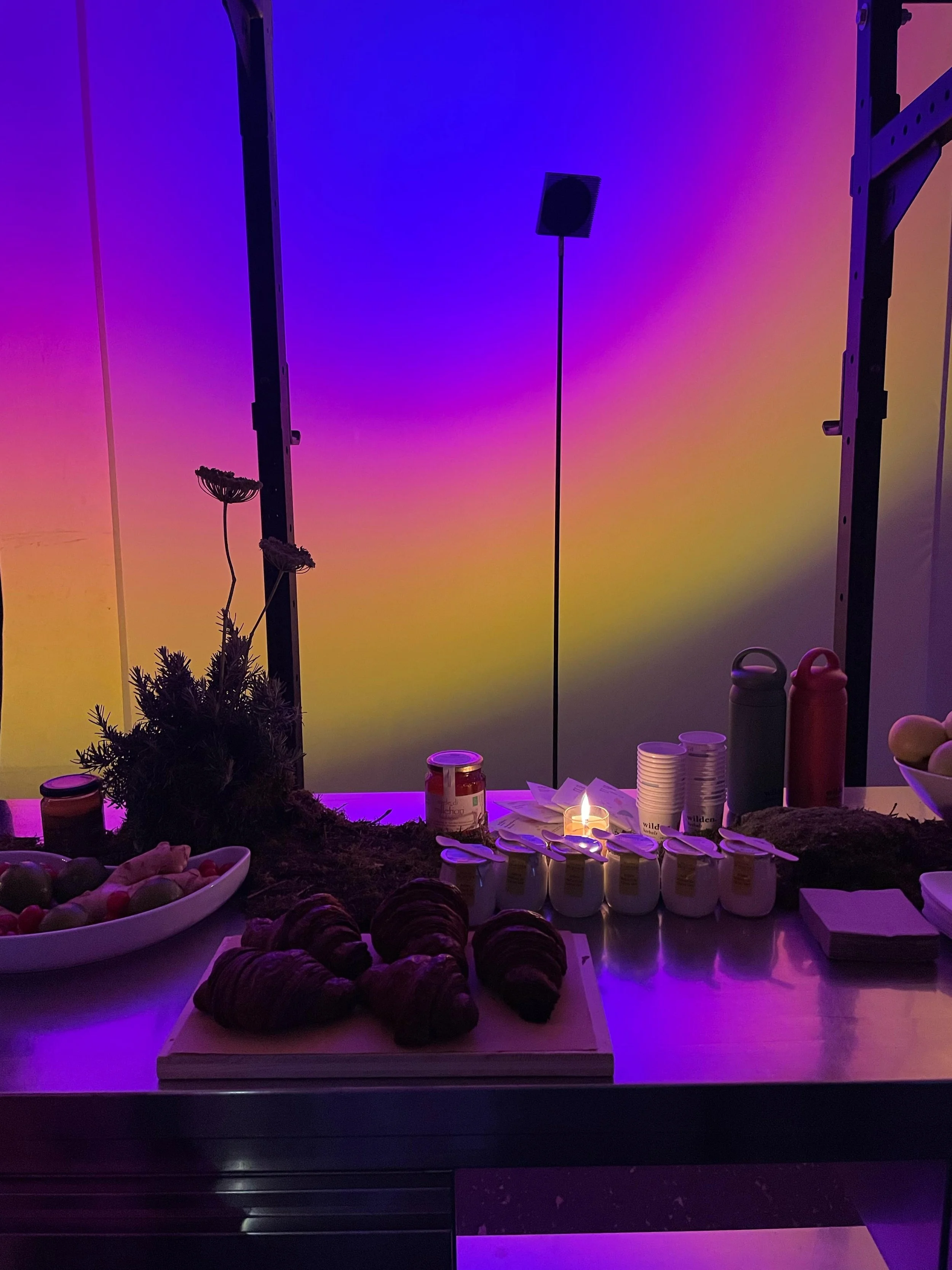 Un buffet con dolci, yogurt e frutta, con luci colorate sullo sfondo