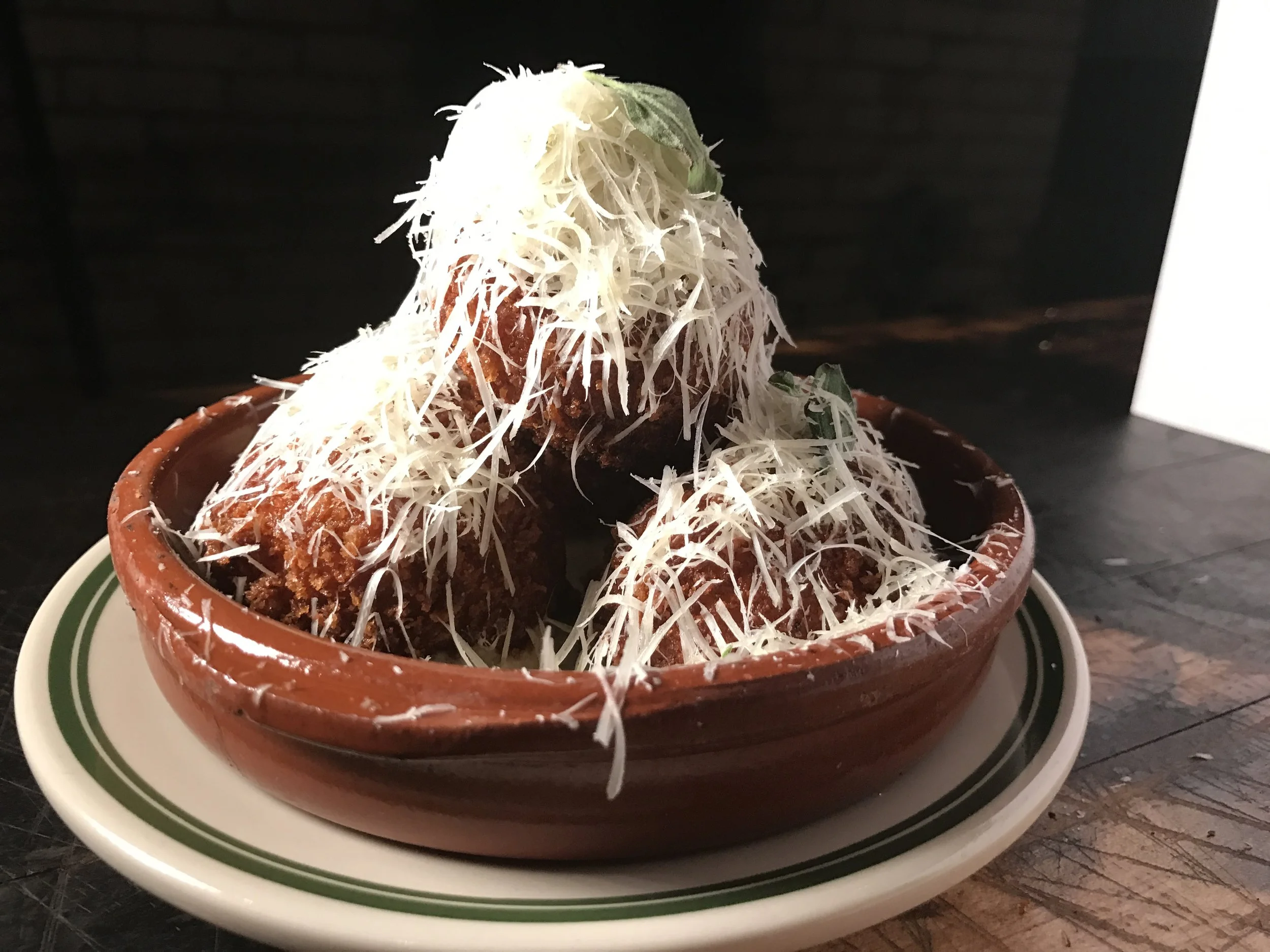 Bowl of tacos topped with shredded cheese and garnished with basil leaves.