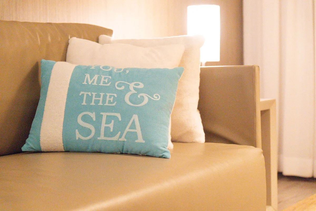 Decorative pillows on a sofa, including one with the text "You, me & the sea."