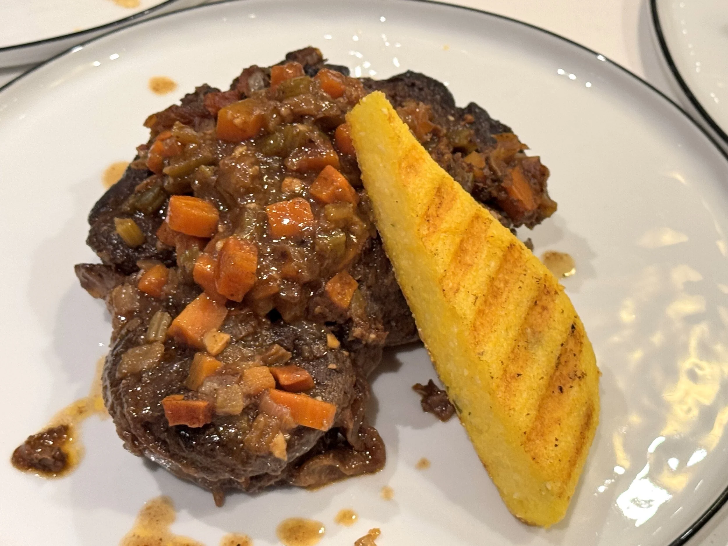 Meatloaf with vegetable gravy and a slice of toasted yellow bread on a white plate.
