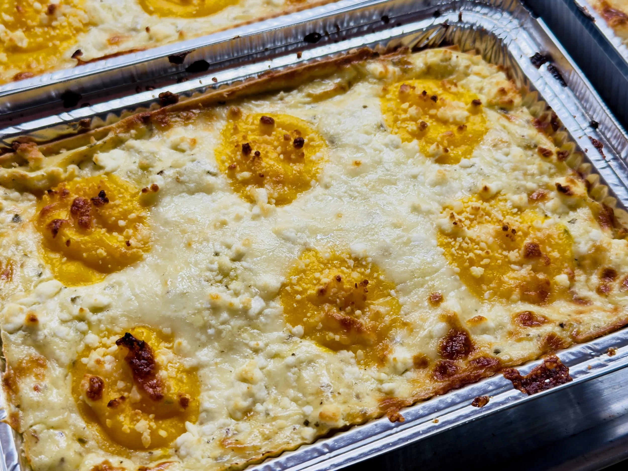 Baked casserole dish with halved boiled eggs, melted cheese, and a crispy crust in a metal tray.