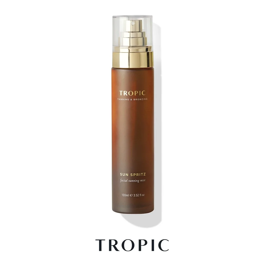 A brown spray bottle labeled 'Tropic Tanning & Bronzing Sun Spritz facial tanning mist' with a clear cap, standing against a white background.