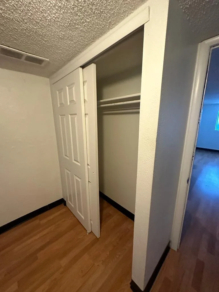 Empty closet with white sliding doors and a metal rod for hanging clothes