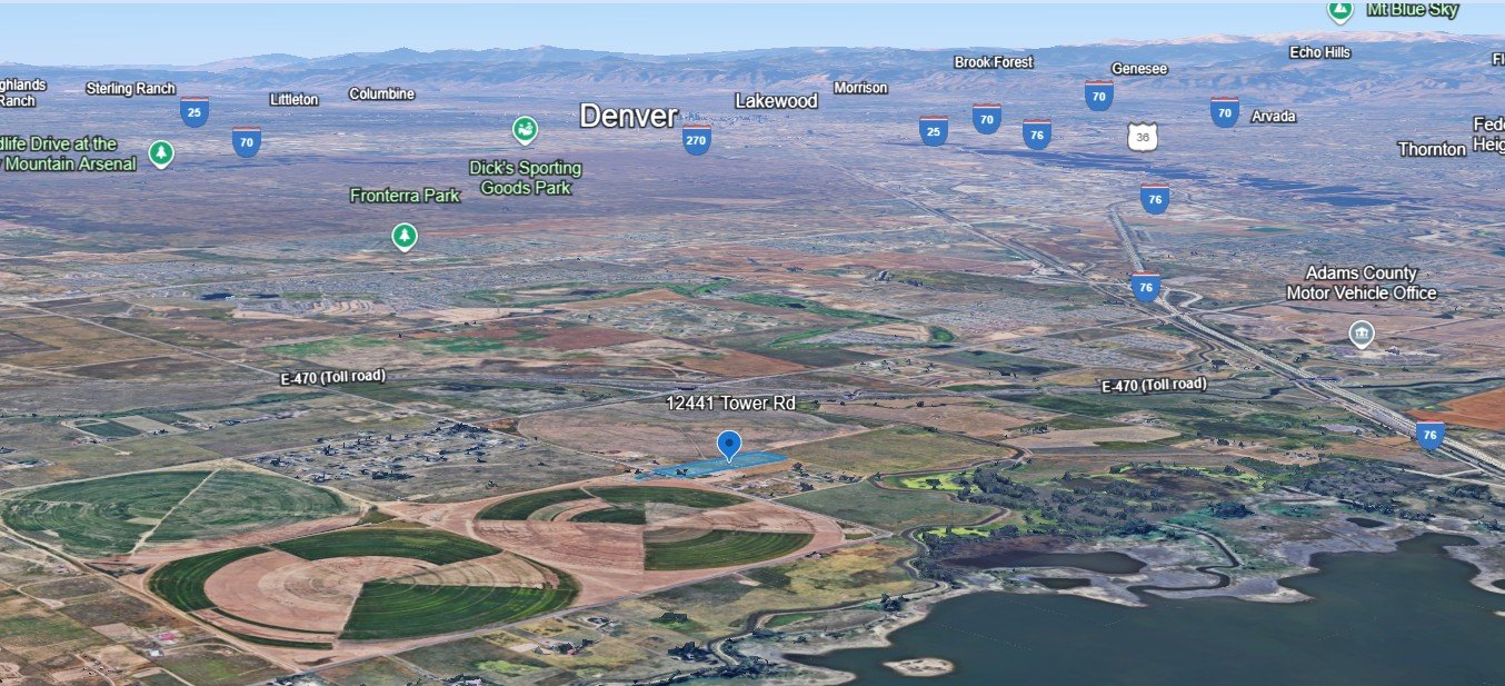 Aerial view of Denver, Colorado, showing farmland, lakes, highways, and the city skyline in the distance.