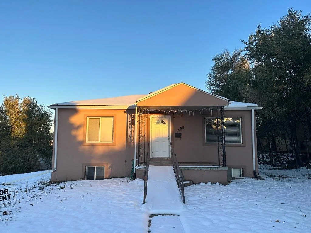 Front view of a house with a snow-covered yard, a porch with a canopy, and a 'For Rent' sign in the yard.