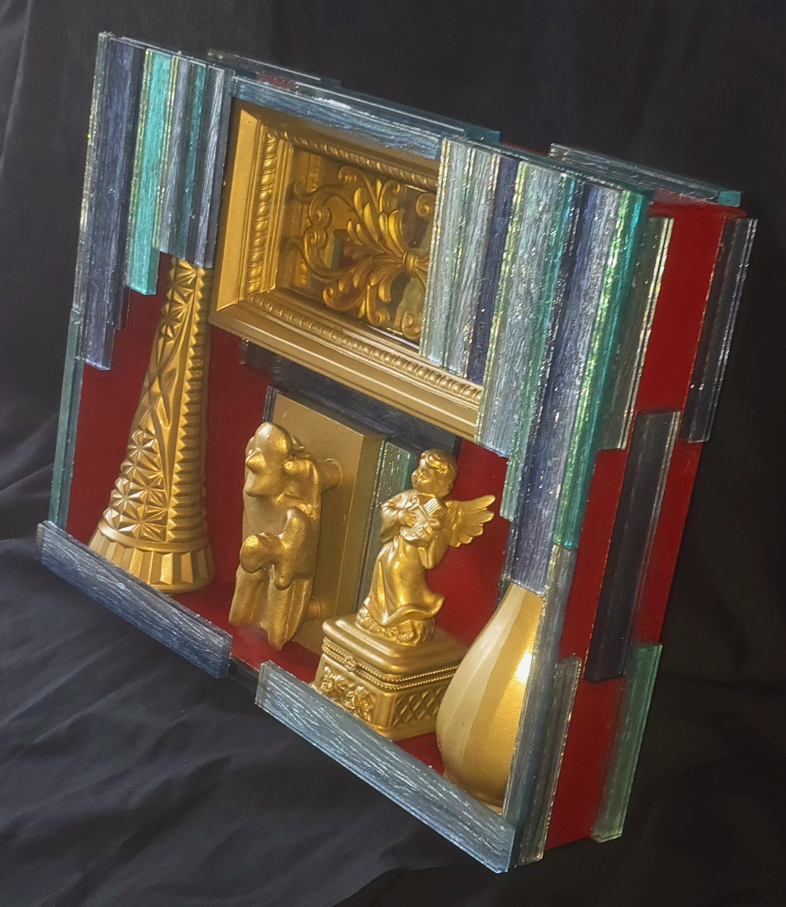 Right view of a handmade, hand-painted assemblage box containing painted and glued found objects.