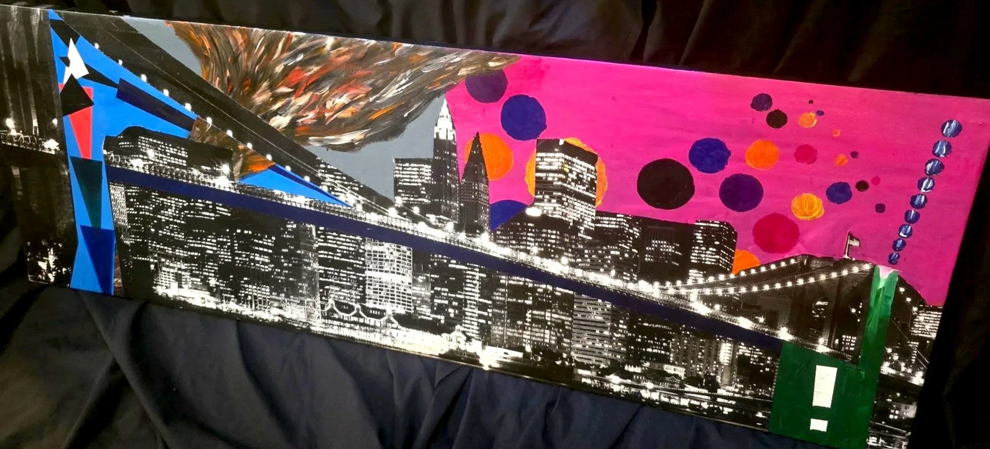 City skyline painting by Andrew Hall with vibrant abstract expressionist flourishes, photographed casually against a neutral background.