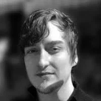 Black and white portrait of a young man with wavy hair and a slight smile.