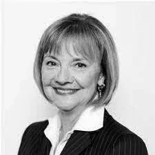 A black and white portrait of a smiling woman with shoulder-length hair, wearing a pinstripe suit and white shirt.