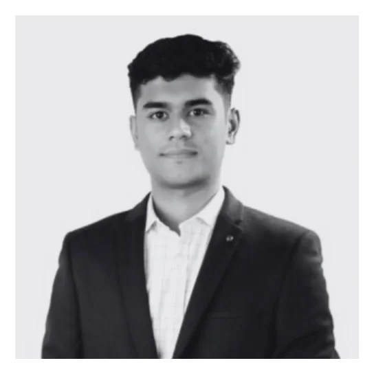 A young man in a suit and collared shirt posing for a professional photo against a light background.