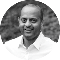 Black and white portrait of a smiling man with a bald head wearing a collared shirt.
