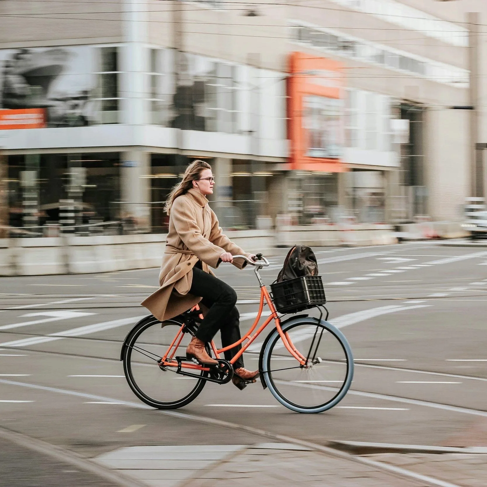 Woman riding a bike across a city street with motion blur background.