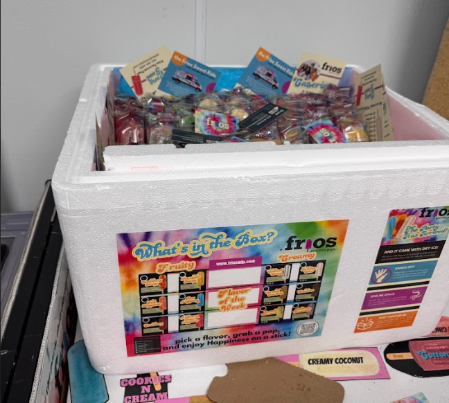 A large white insulated frios cooler box filled with pops and promotional flyers.