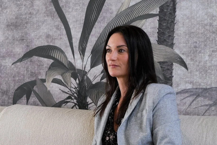 Michelle Domenghini, certified hypnotherapist, seated in a calm indoor setting with plants