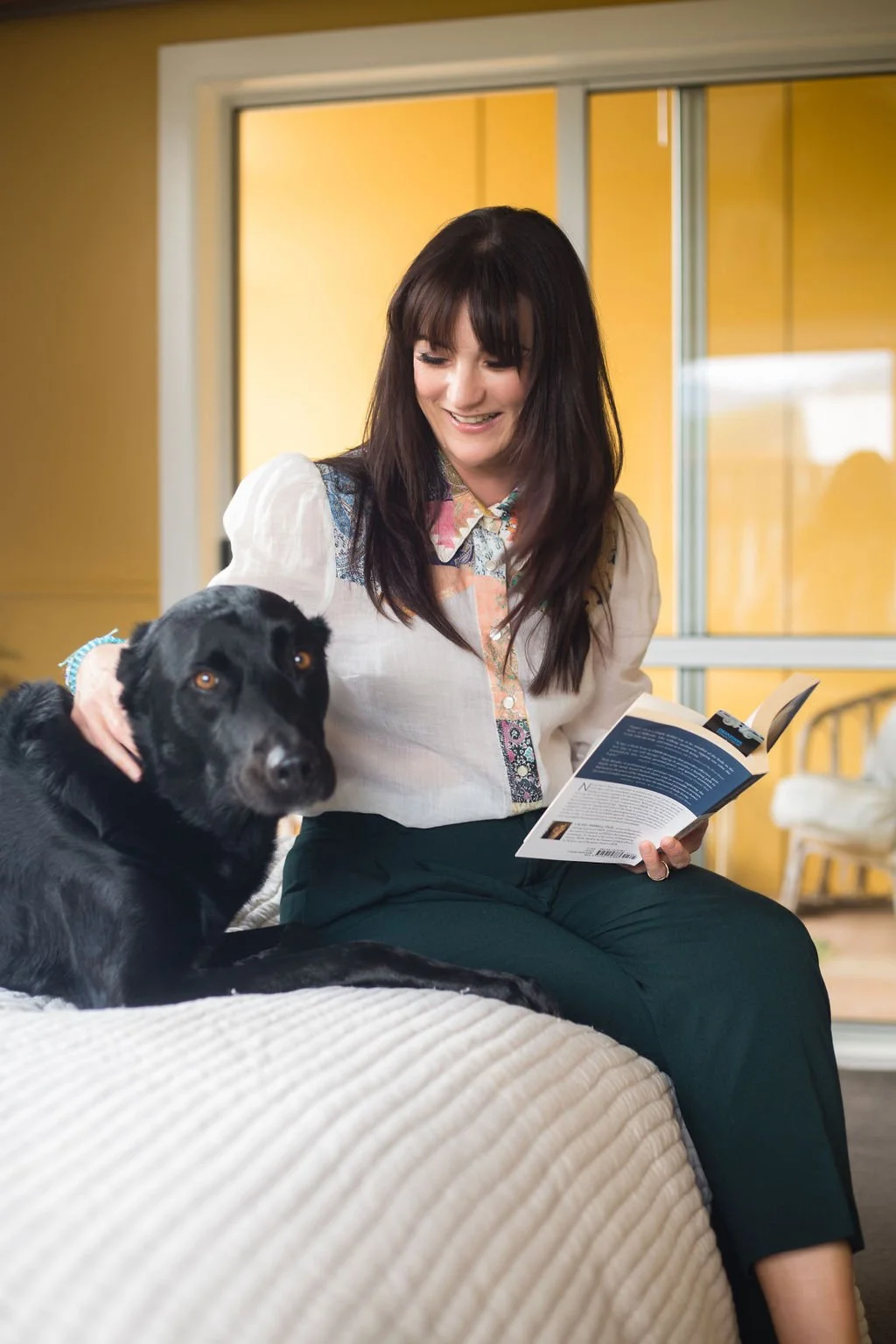 Michelle Domenghini, RTT practitioner, sitting with her black dog in a warm, welcoming room.