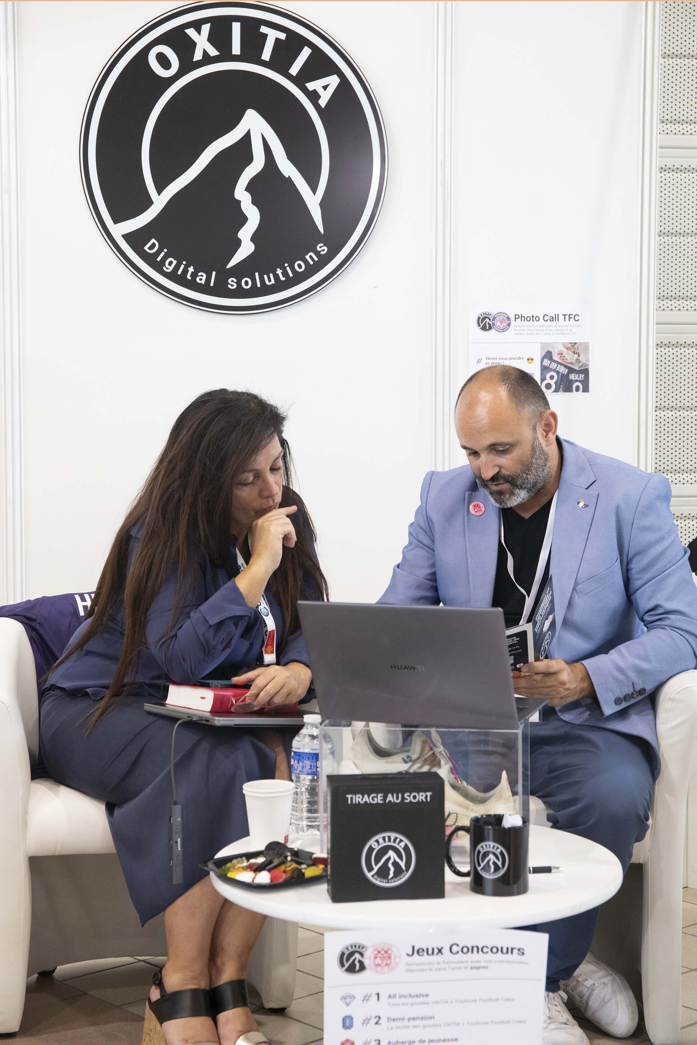 Lors d’un événement, le photographe François Fauré a capturé des participants en pleine discussion, illustrant l’interaction et l’engagement.  L’ambiance professionnelle était renforcée par la présence du logo Oxitia.  Le décor moderne, aux couleurs 