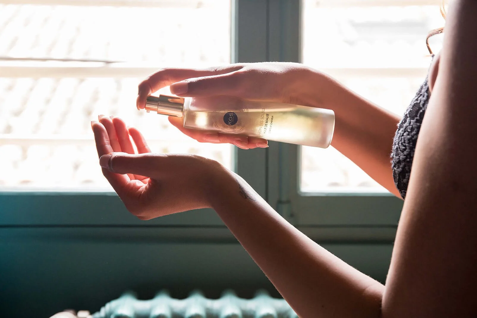 Photographie d’un produit de soin de la peau mettant en valeur les mains et le flacon dans un cadre professionnel baigné de lumière naturelle.  Une prise de vue artistique d’un produit de beauté sur fond lumineux et apaisant, capturant les détails d’