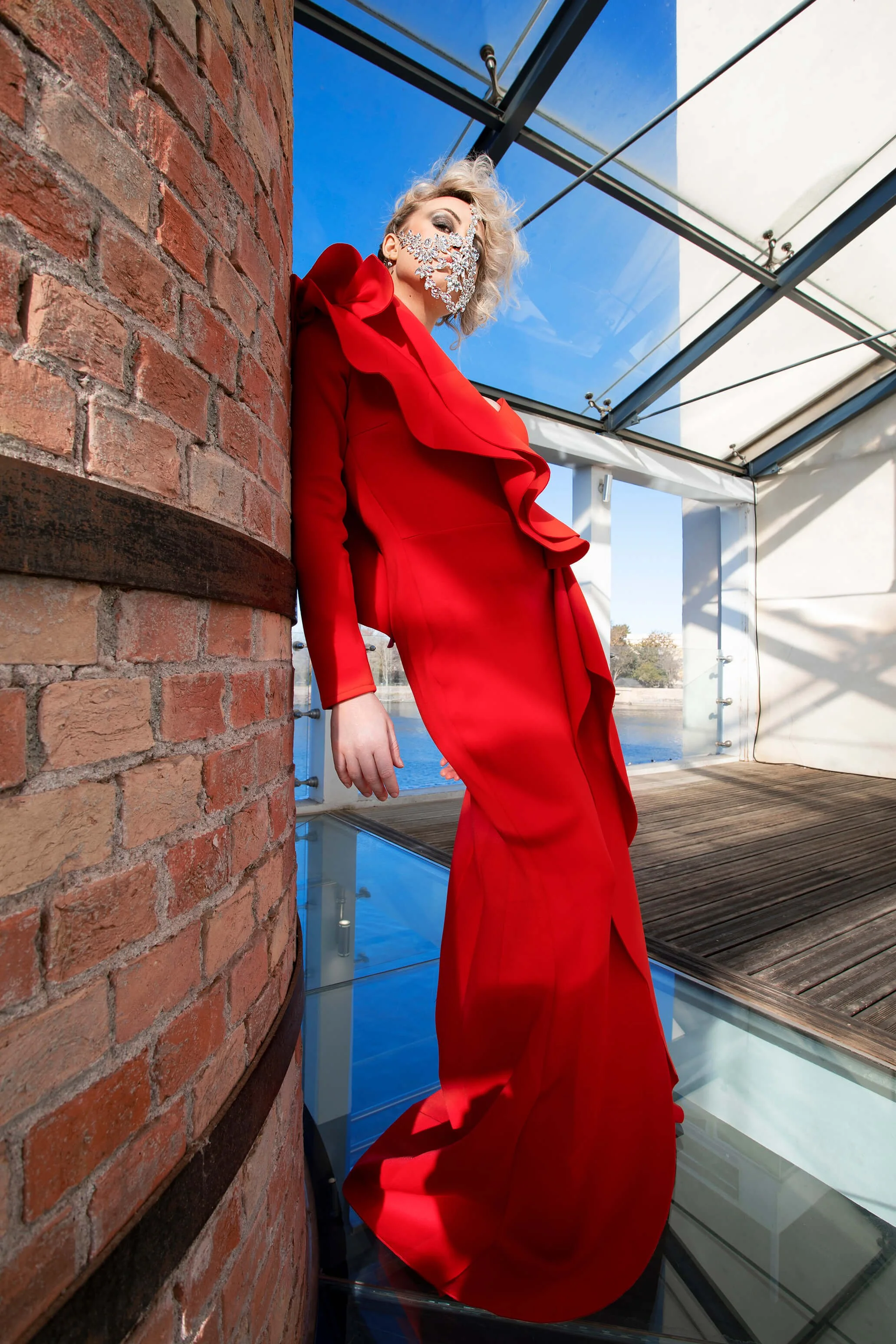 Modèle en robe rouge dans un environnement en verre, mettant en avant l'art de la coiffure.
