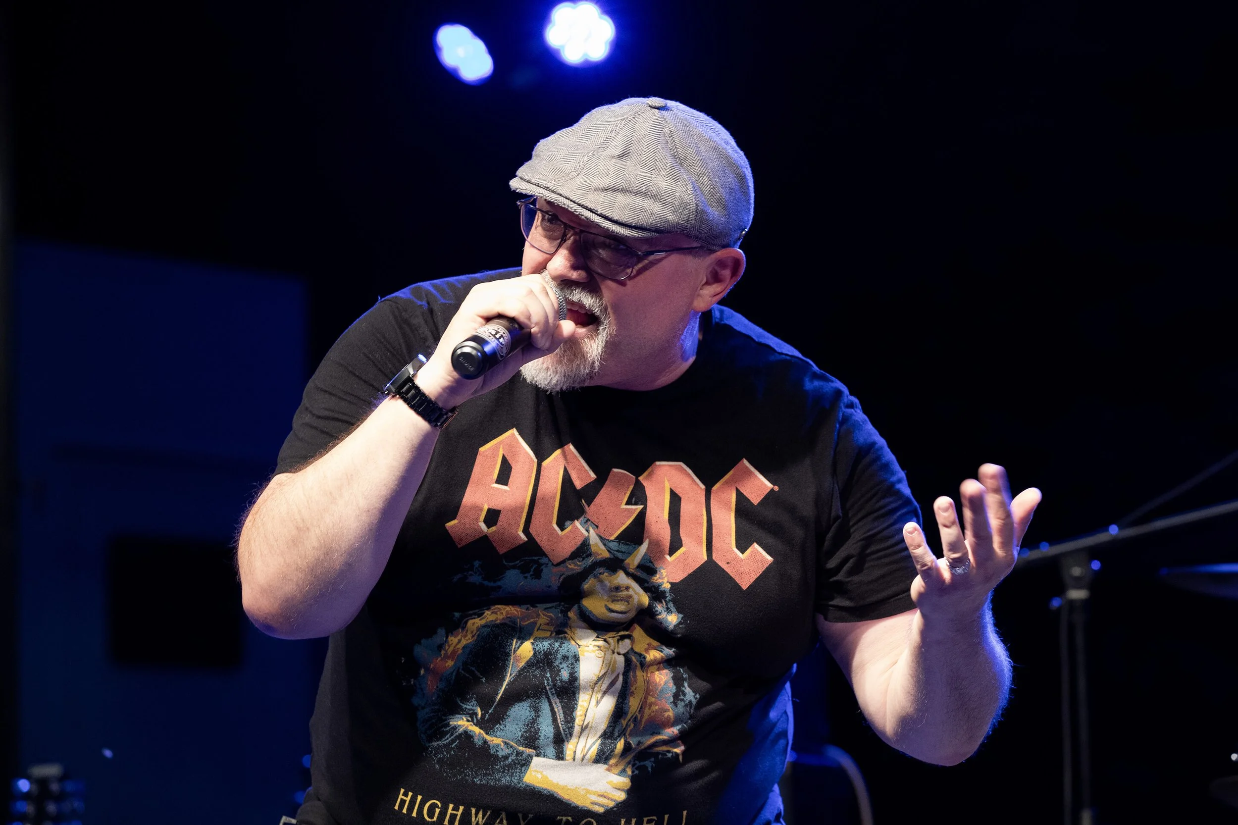 François Fauré, photographe, immortalise l’énergie vibrante d’un événement musical.  Son objectif capte l’essence même de la performance, mettant en lumière le style unique de l’artiste.  Un chanteur passionné, vêtu d’un t-shirt AC/DC, s’exprime sur 