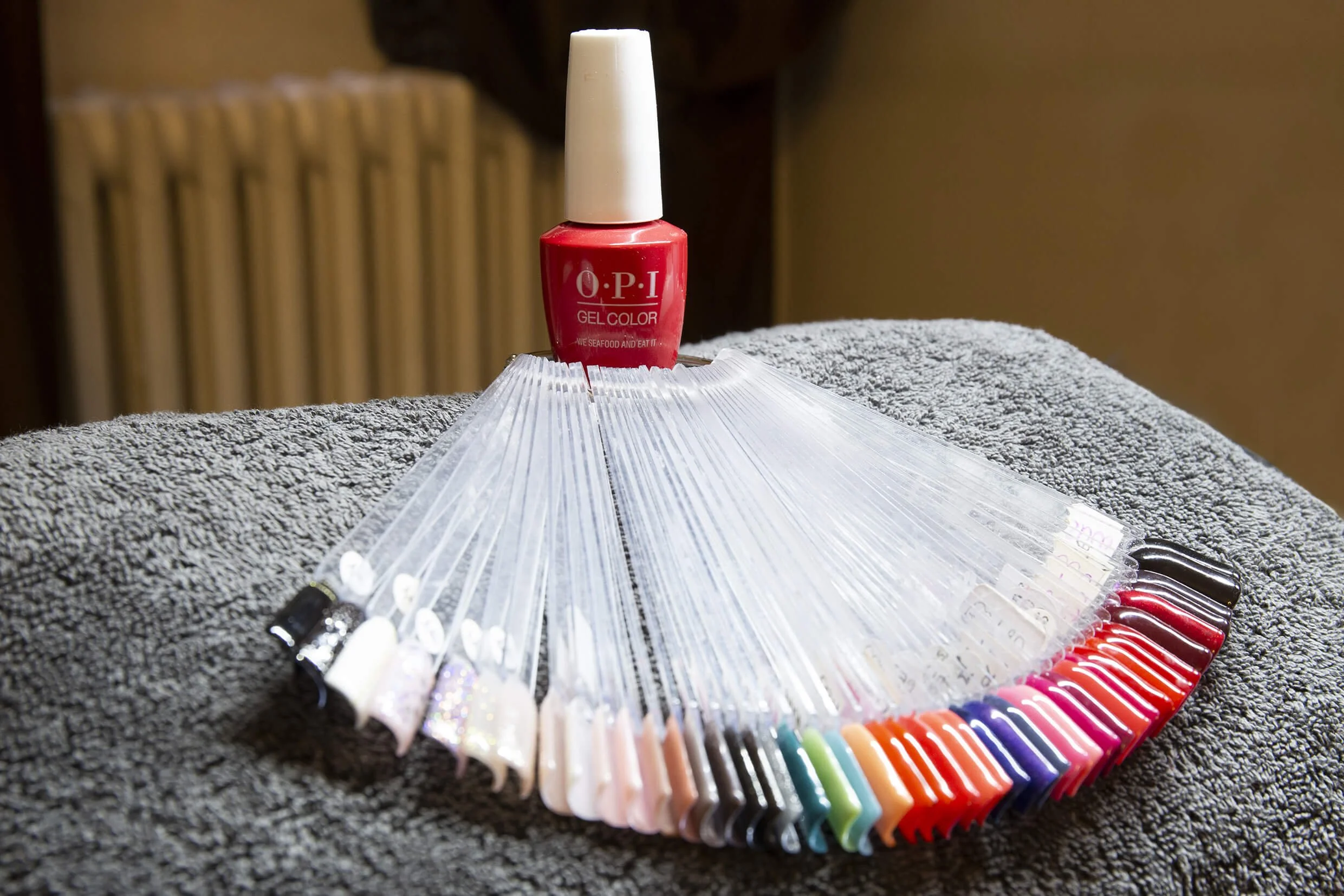 Un flacon de vernis à ongles OPI rouge se détache sur un fond de palette de couleurs variées.  La photo professionnelle met en valeur le style et les couleurs du vernis à ongles OPI.  Un flacon de vernis à ongles OPI est photographié avec des échanti