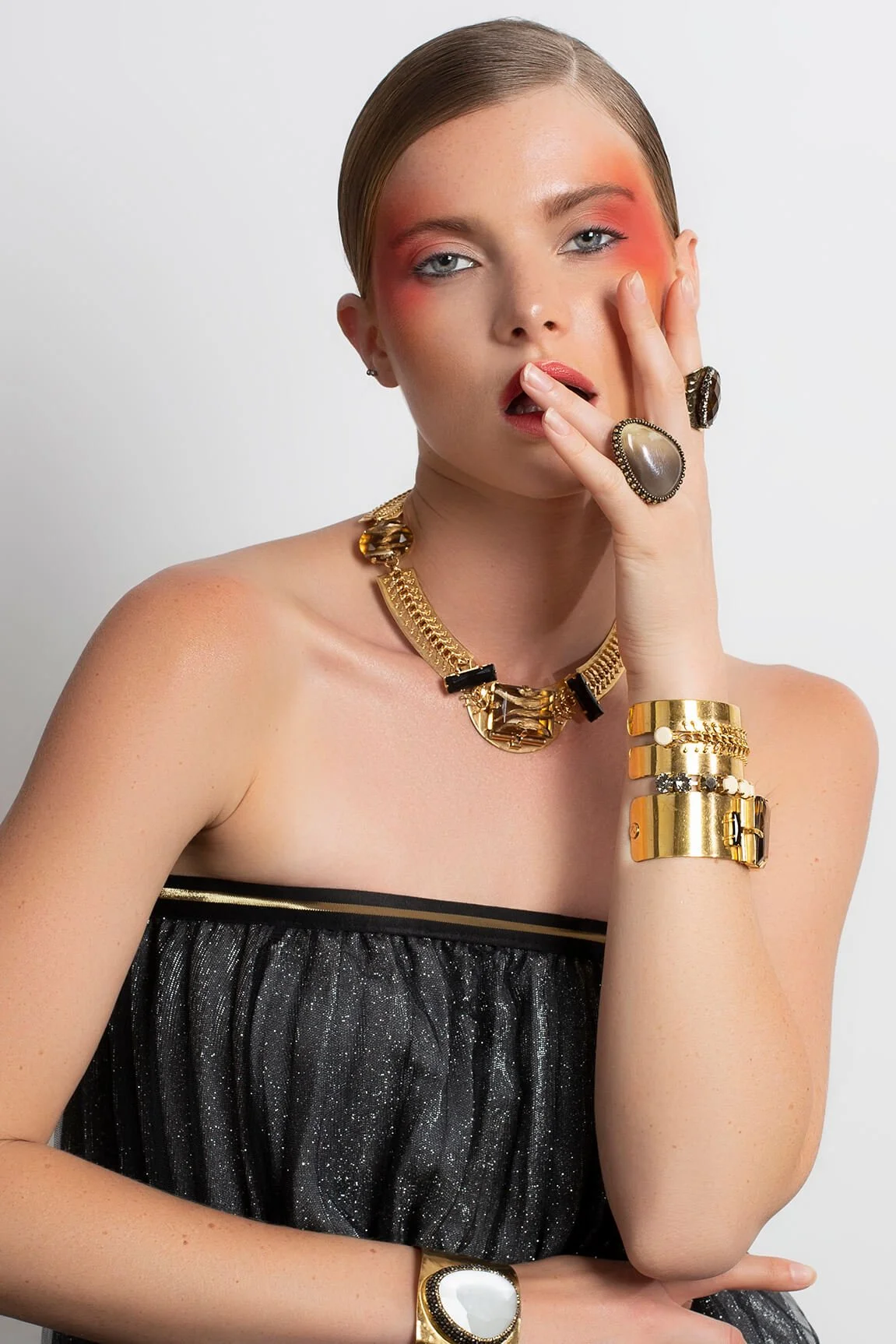 Modèle portant des bijoux en or avec une coiffure sophistiquée.