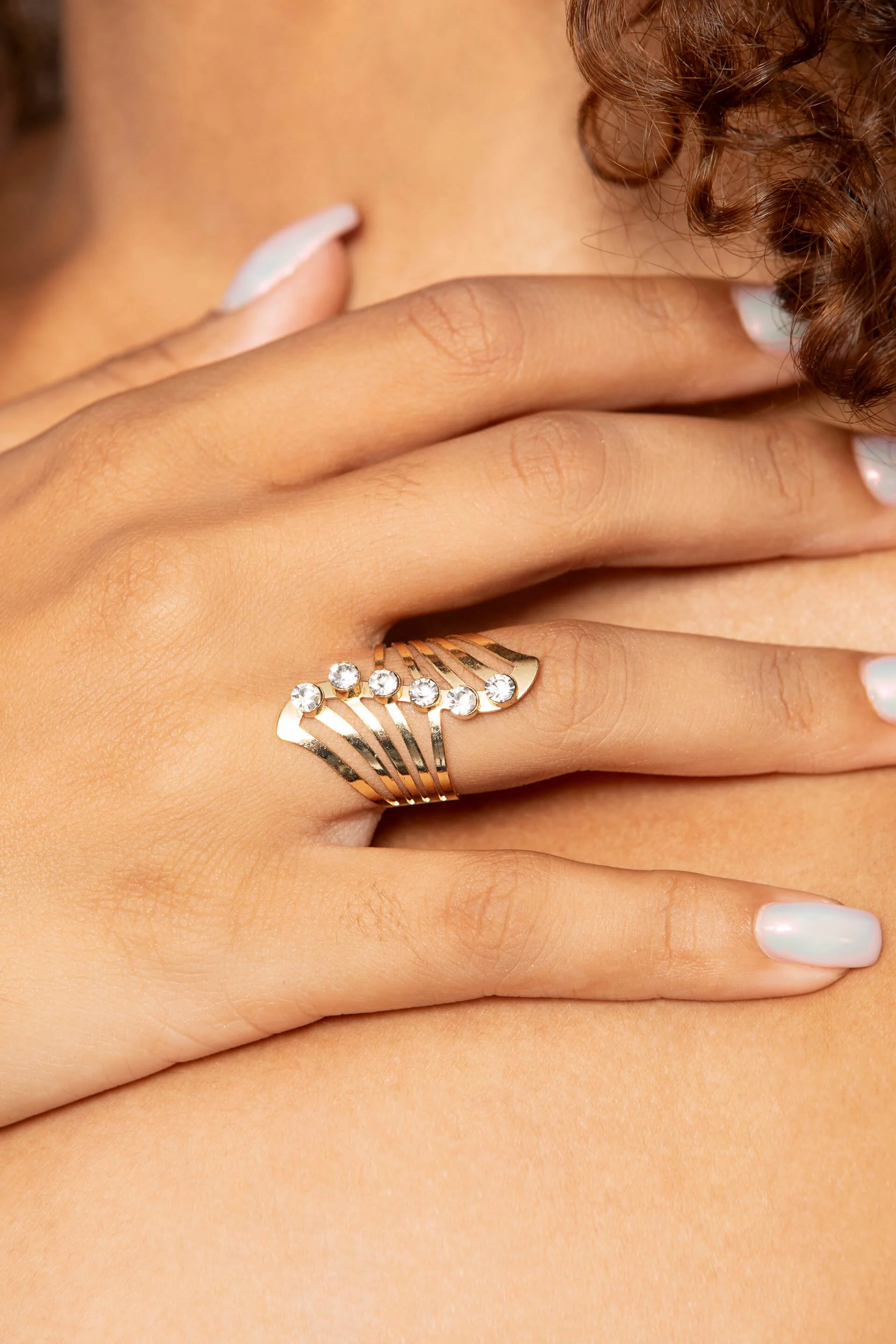 Gros plan d'une main avec un anneau en or et strass.