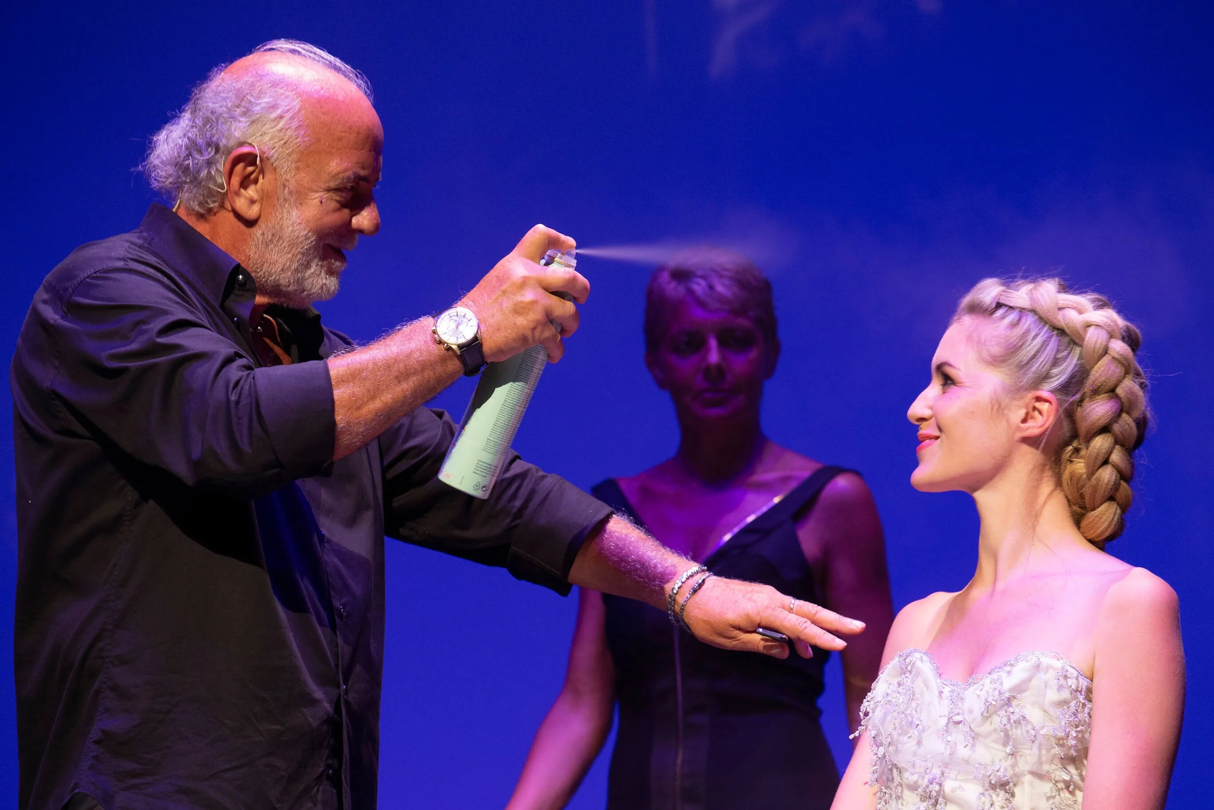 Un photographe professionnel capturant l'art de la coiffure avec des couleurs vibrantes.
Application de spray coiffant par un expert en coiffure sur une modèle.
Style photographique mettant en avant la coiffure et les détails artistiques.
Décor color