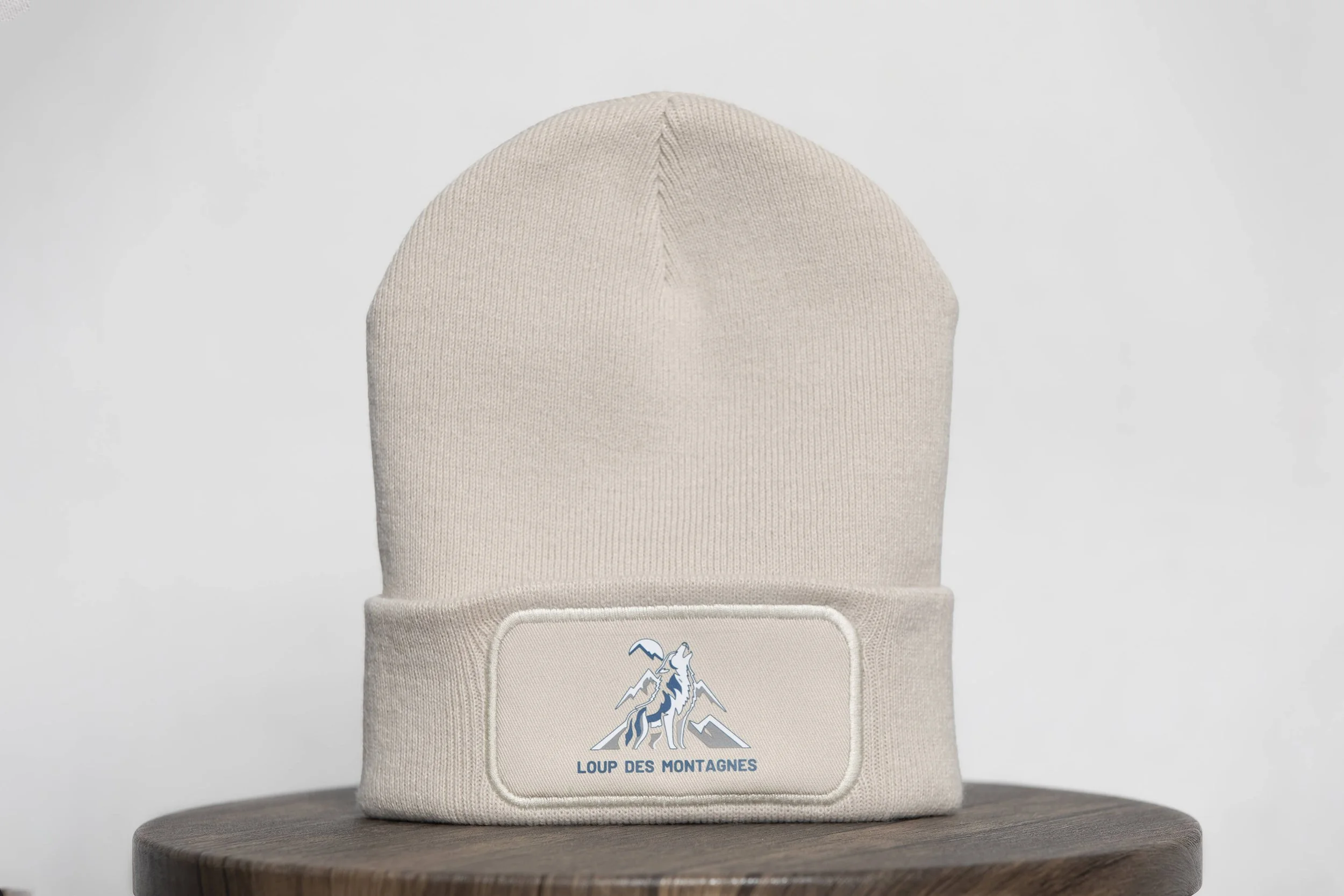 Bonnet beige avec logo Loup des Montagnes sur un fond neutre