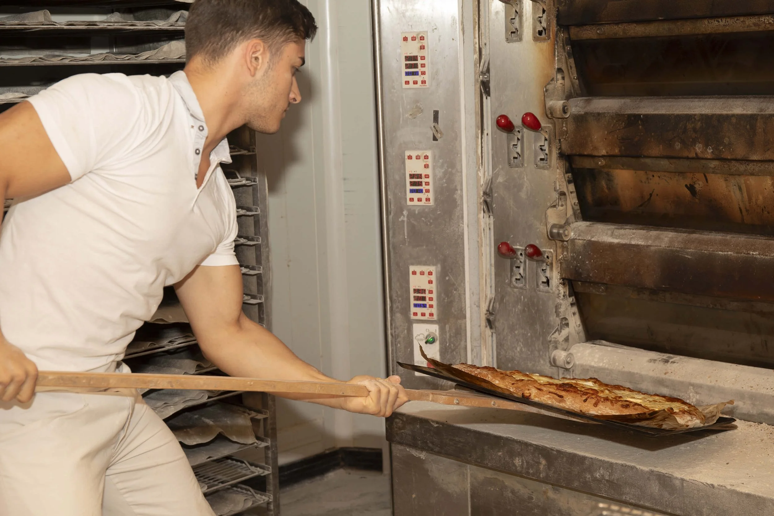 Un boulanger professionnel sort du pain chaud du four, mettant en lumière son expertise et son environnement de travail.

- Ambiance-boulangerie.jpg : Ambiance d’une boulangerie avec un boulanger en action, illustrant le style photographique de Franç