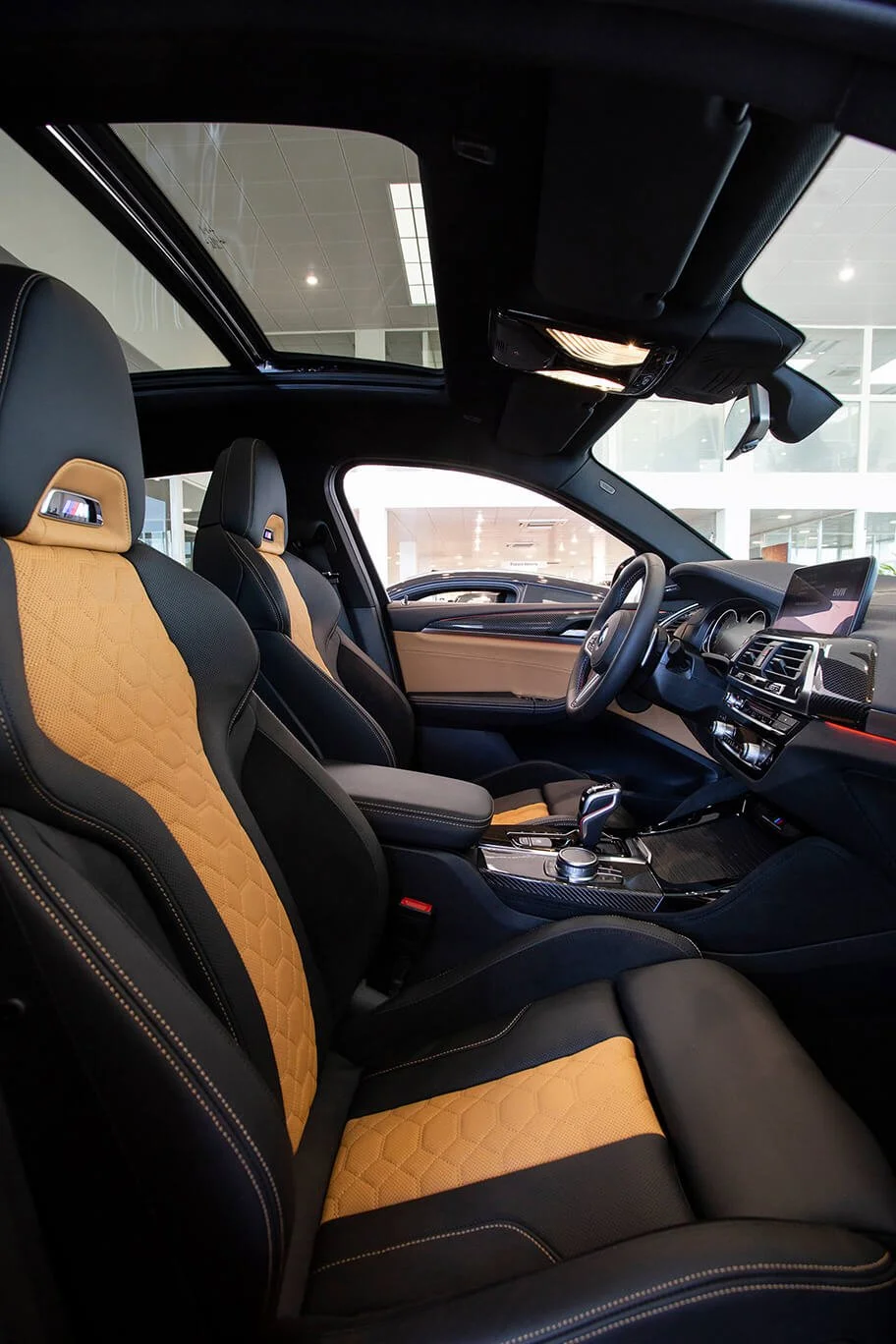 Vue intérieure d’une voiture moderne, mettant en avant ses sièges en cuir noir et orange, capturée par François Fauré.