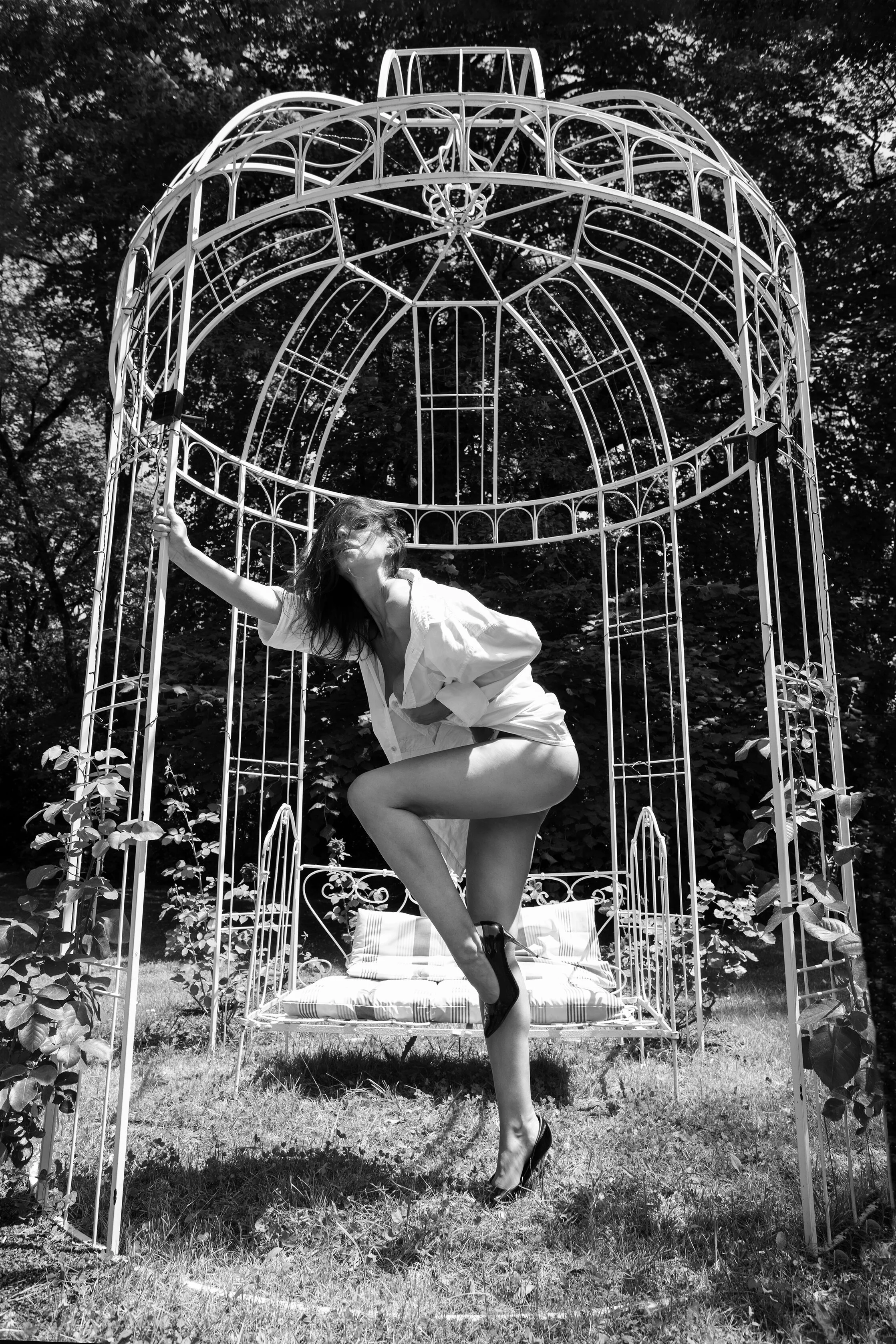 Femme posant en lingerie dans une cage en plein air, en noir et blanc.