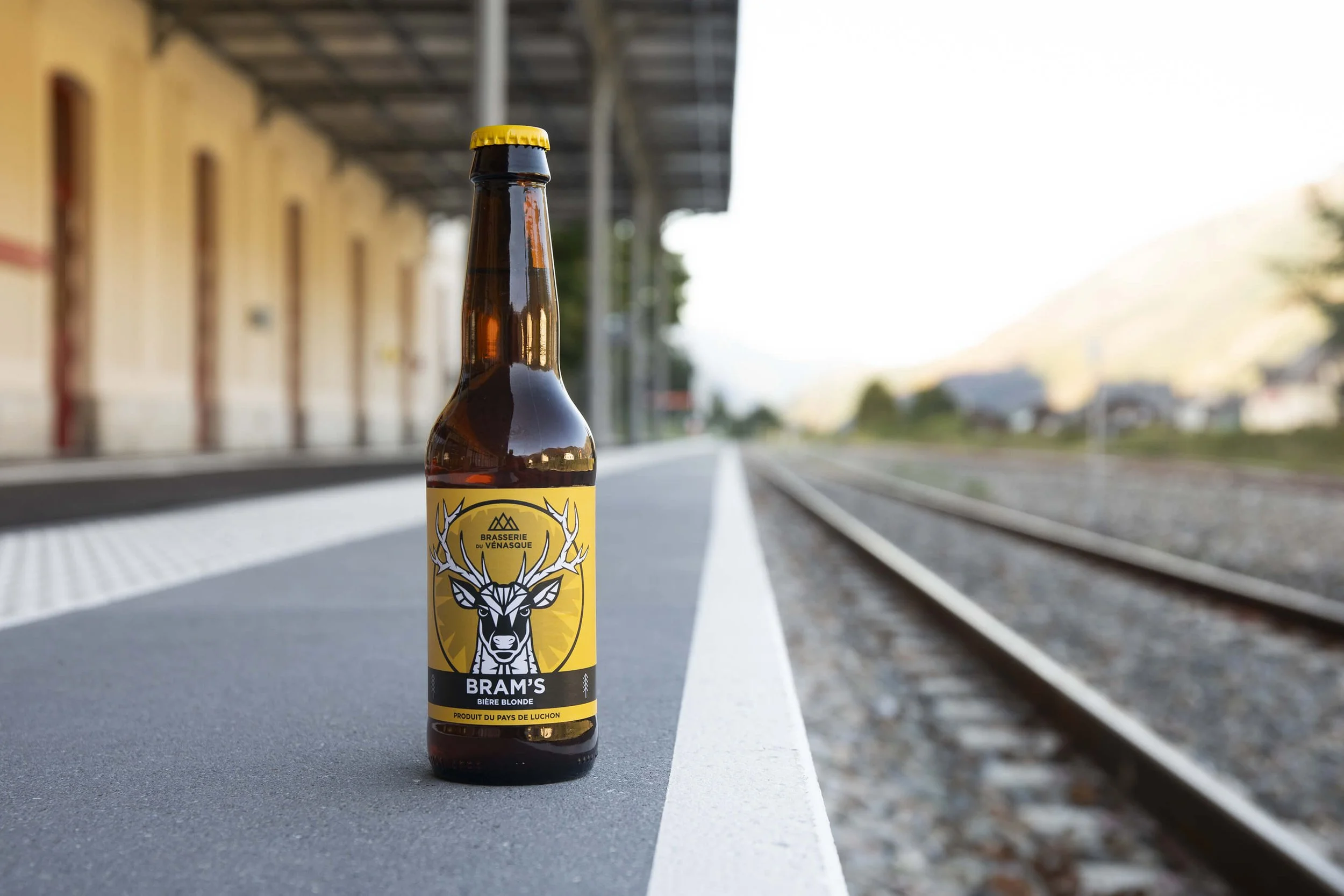 Bouteille de bière blonde de la brasserie Bram's sur un quai de gare
Photo artistique d'une bière blonde sur un quai, avec arrière-plan flou
Bière de la brasserie du Venasque, mise en valeur sur un décor de gare
Style photographique moderne mettant e