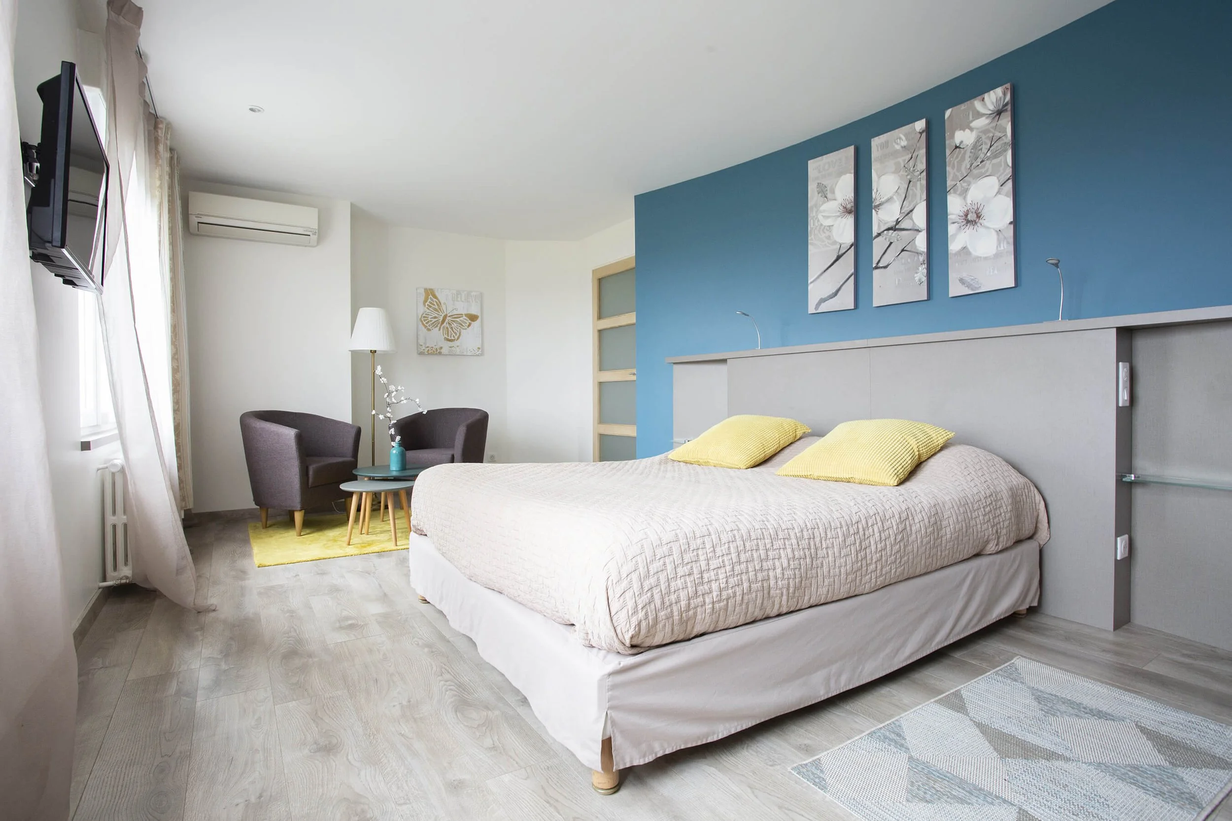 Cette chambre moderne, photographiée par François Fauré, se distingue par son décor élégant et ses couleurs apaisantes.  Le style photographique de Fauré met en valeur la luminosité de la pièce, agrémentée de touches de jaune et de bleu.  Le décor pr