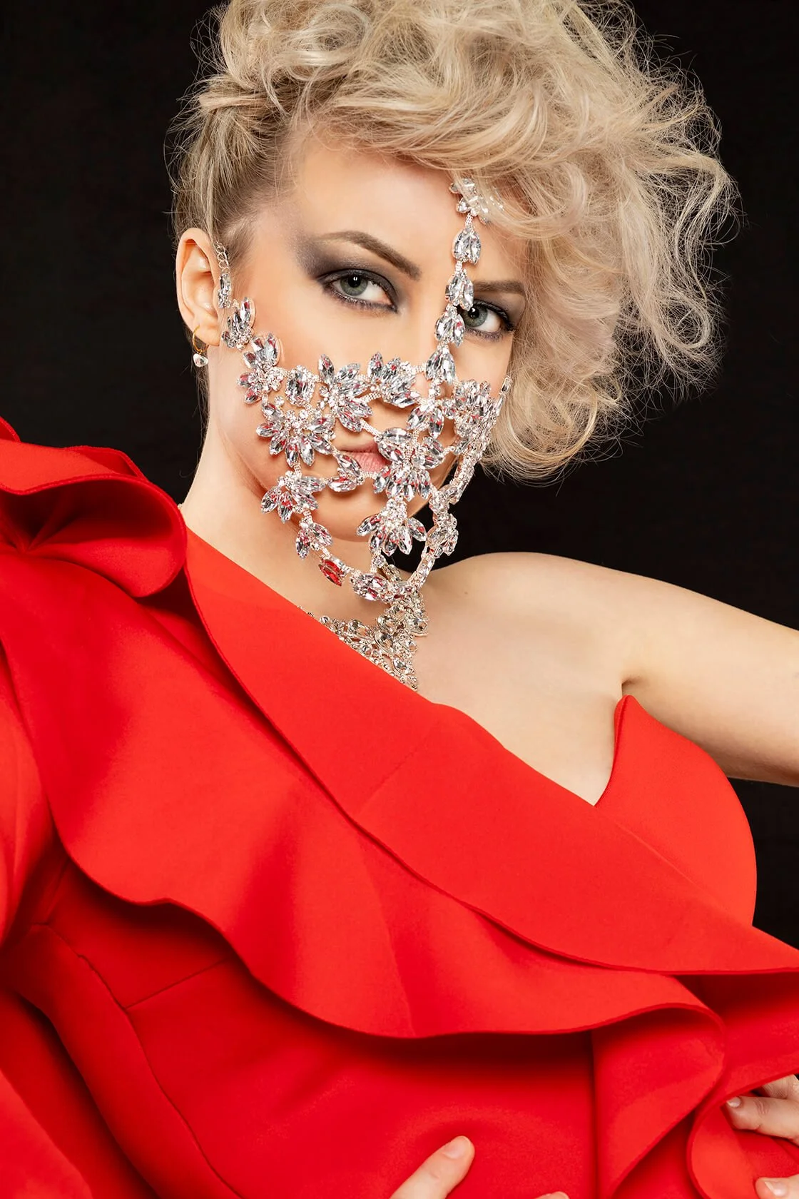 Coiffure professionnelle mettant en valeur des cheveux blonds et un bijoux sur visage dans un style glamour.