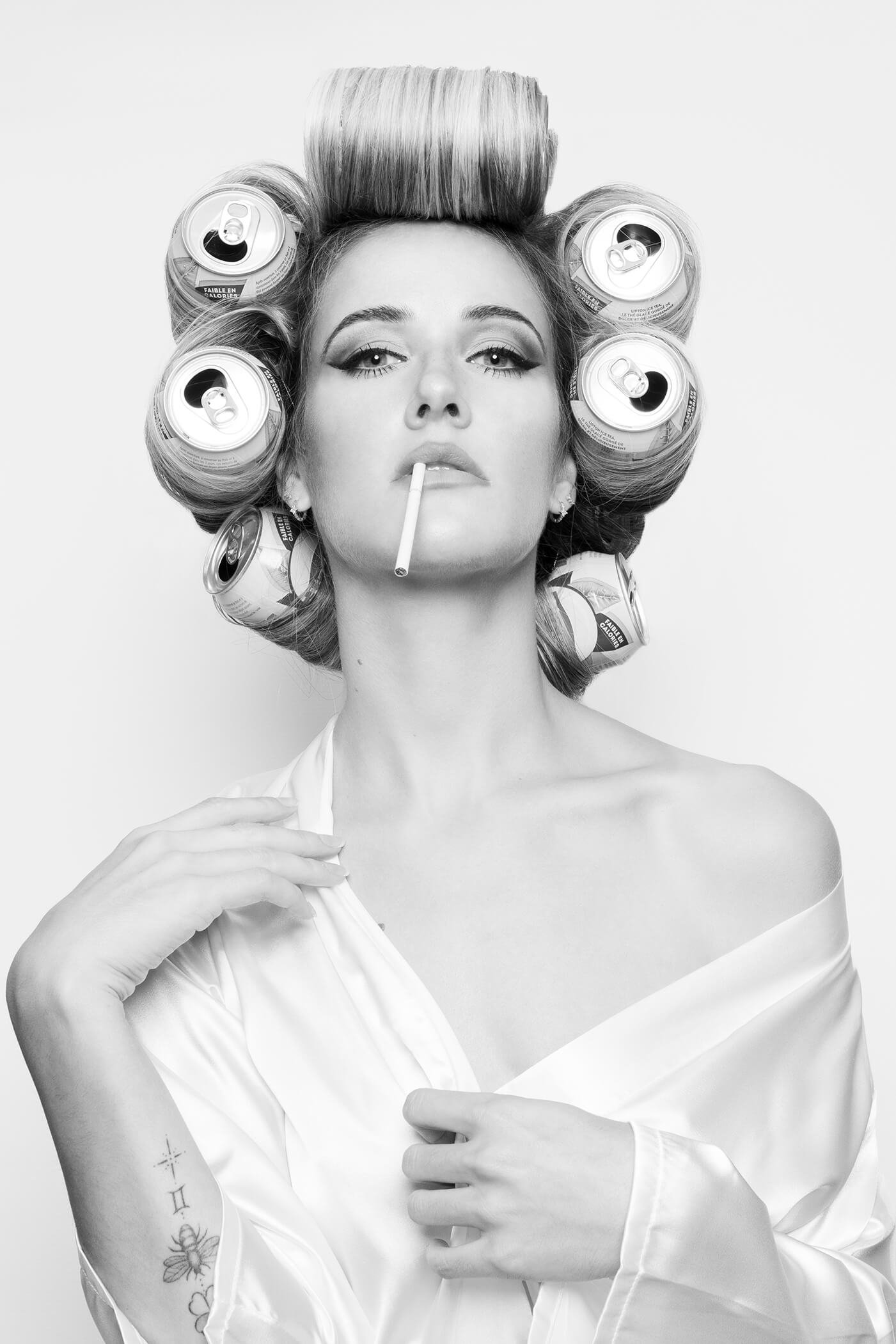 Portrait artistique d'une femme avec des bigoudis en canettes et une cigarette.
Vue d'un photographe sur l'art de la coiffure avec des éléments modernes.
Coiffure créative avec un décor minimaliste et des couleurs contrastées.
Portrait d'un modèle av