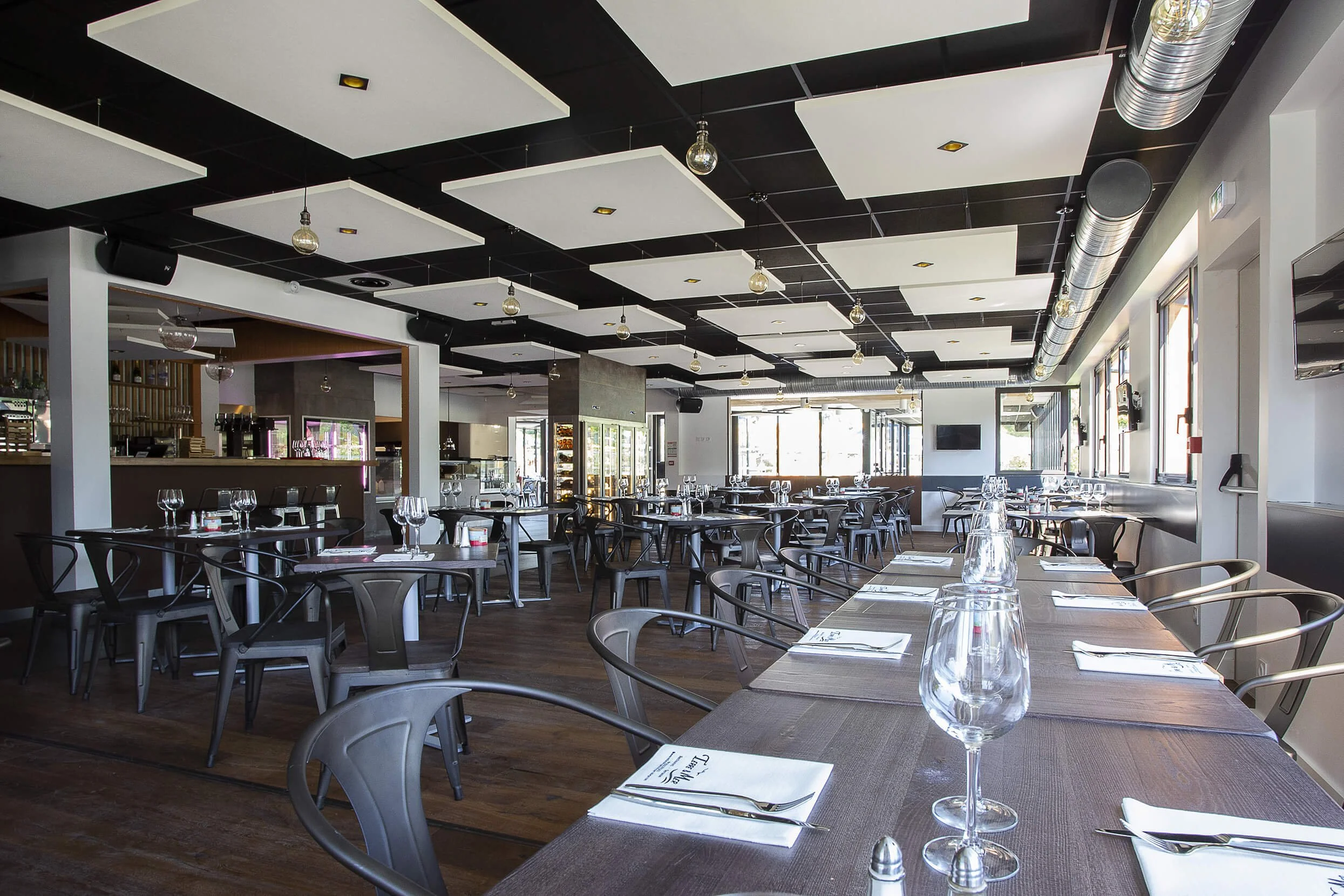 Vue intérieure d’un restaurant moderne, décoré avec élégance et dans des tons neutres. Les tables sont impeccablement dressées et l’éclairage stylé crée une ambiance professionnelle. Le décor met en valeur des meubles contemporains et un design soign